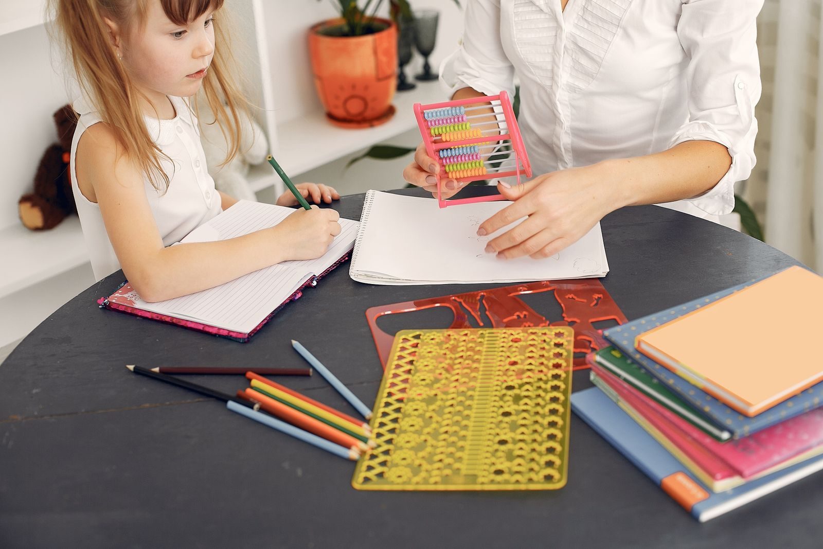 Tutor guiding a student with an abacus on the table