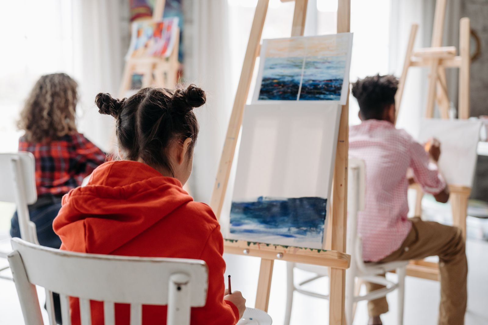 Children painting on easels in art class