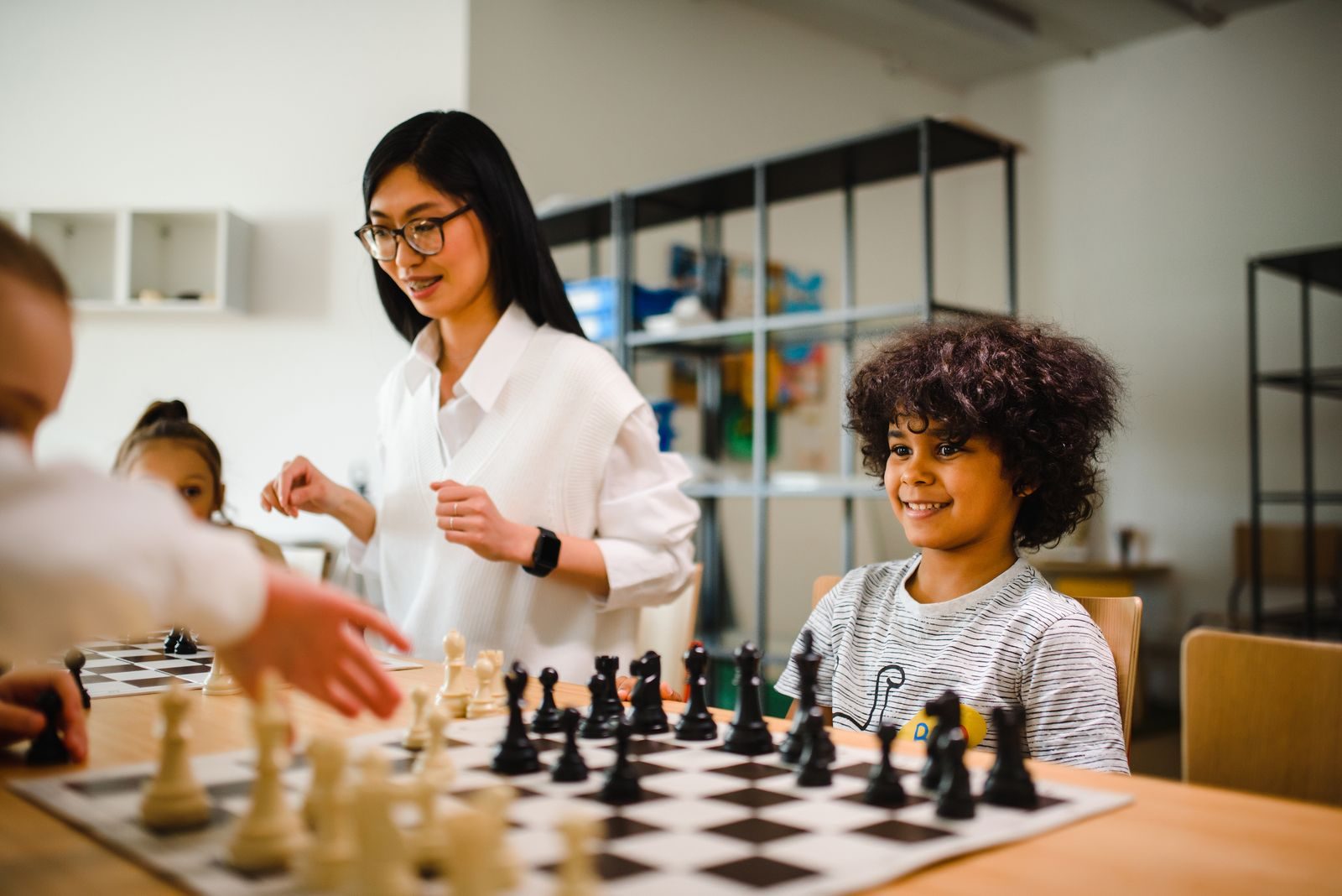 Teacher guiding children during a chess lesson