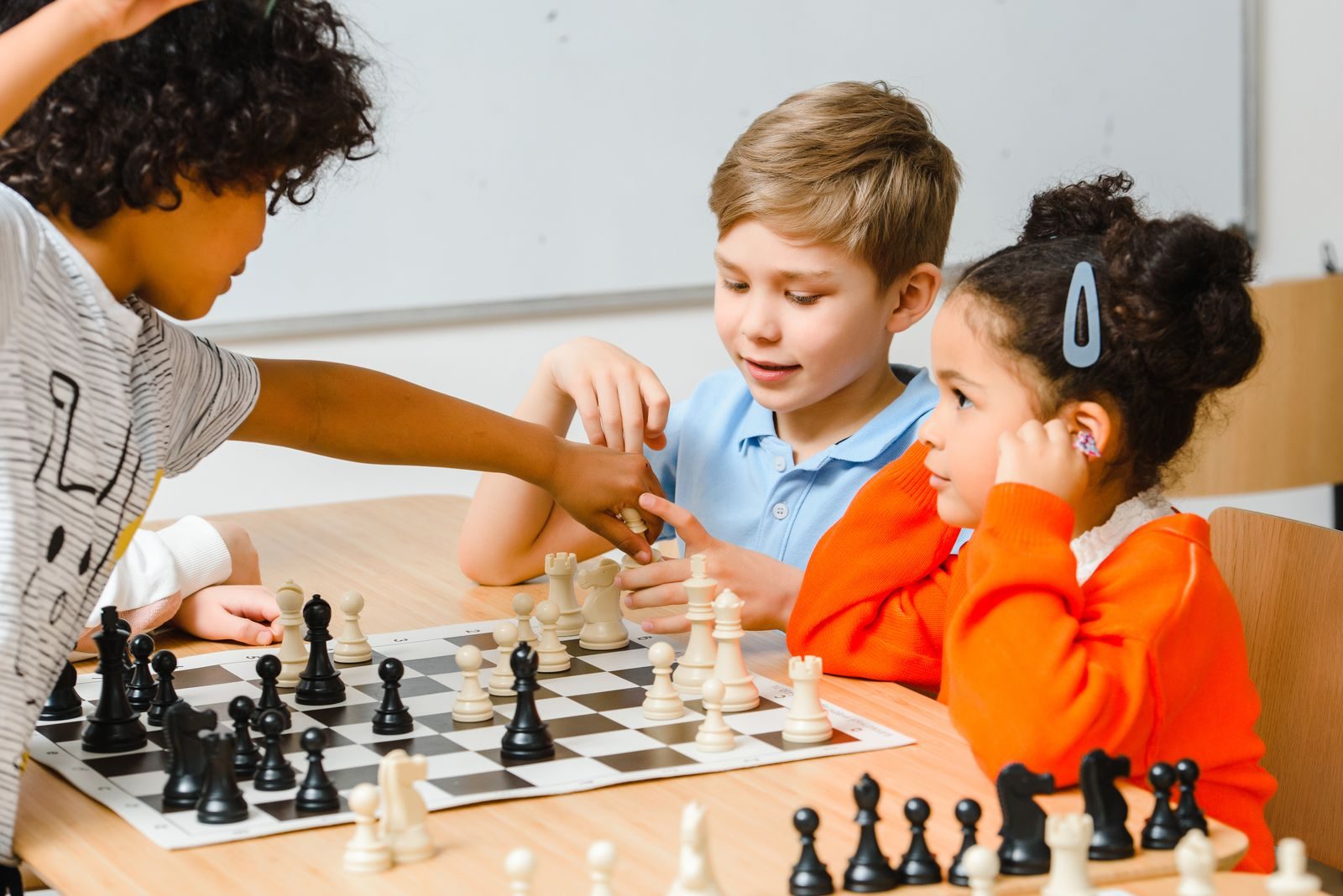 Children playing chess together at a table