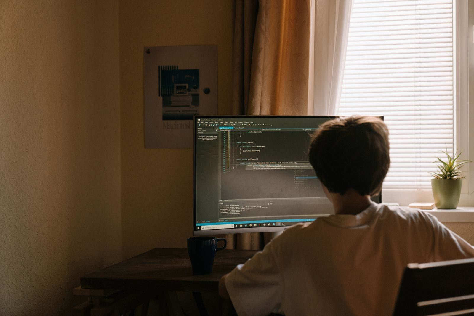 Student coding a game on a computer at his desk