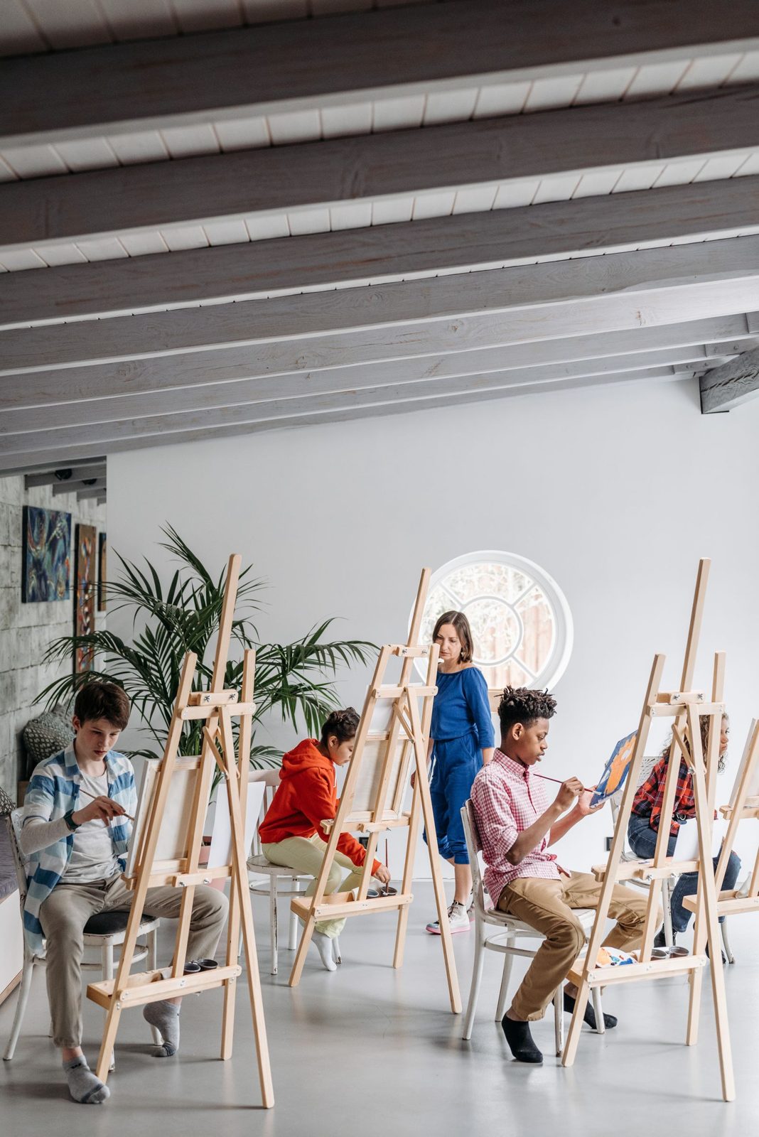 Students painting at easels in a bright studio