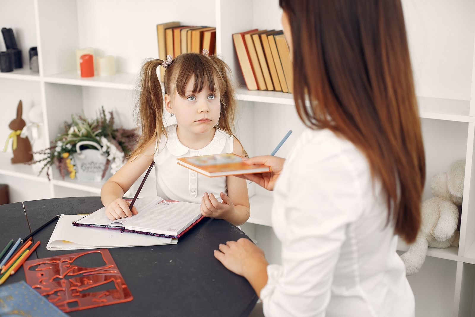 Tutor helping a schoolchild with homework at a desk