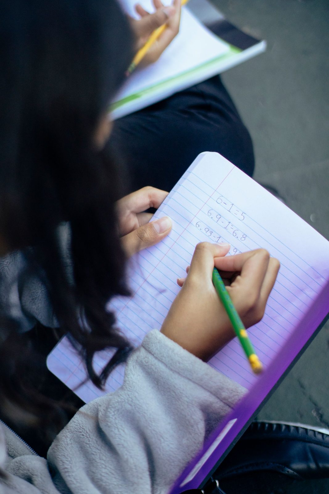 Student writing numbers in a notebook during practice