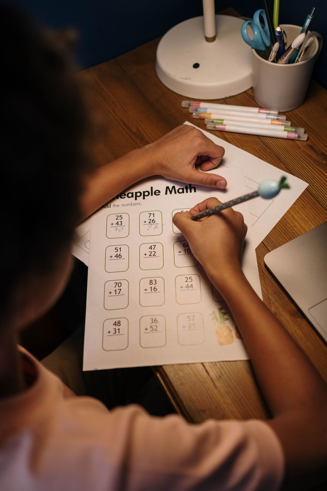 Child solving a maths worksheet with an abacus beside her